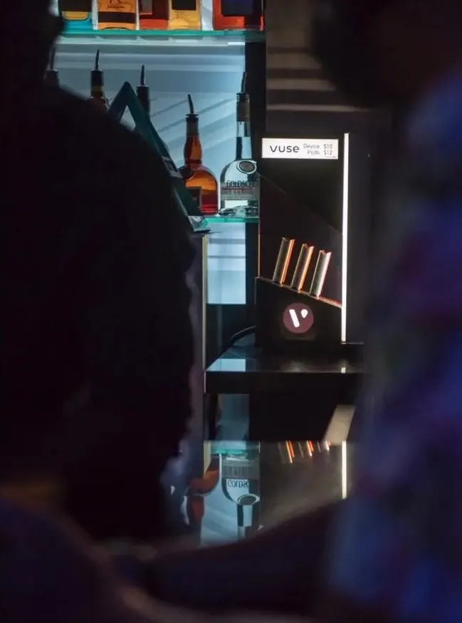 Vuse-branded backbar lit in a bar environment, same DNA